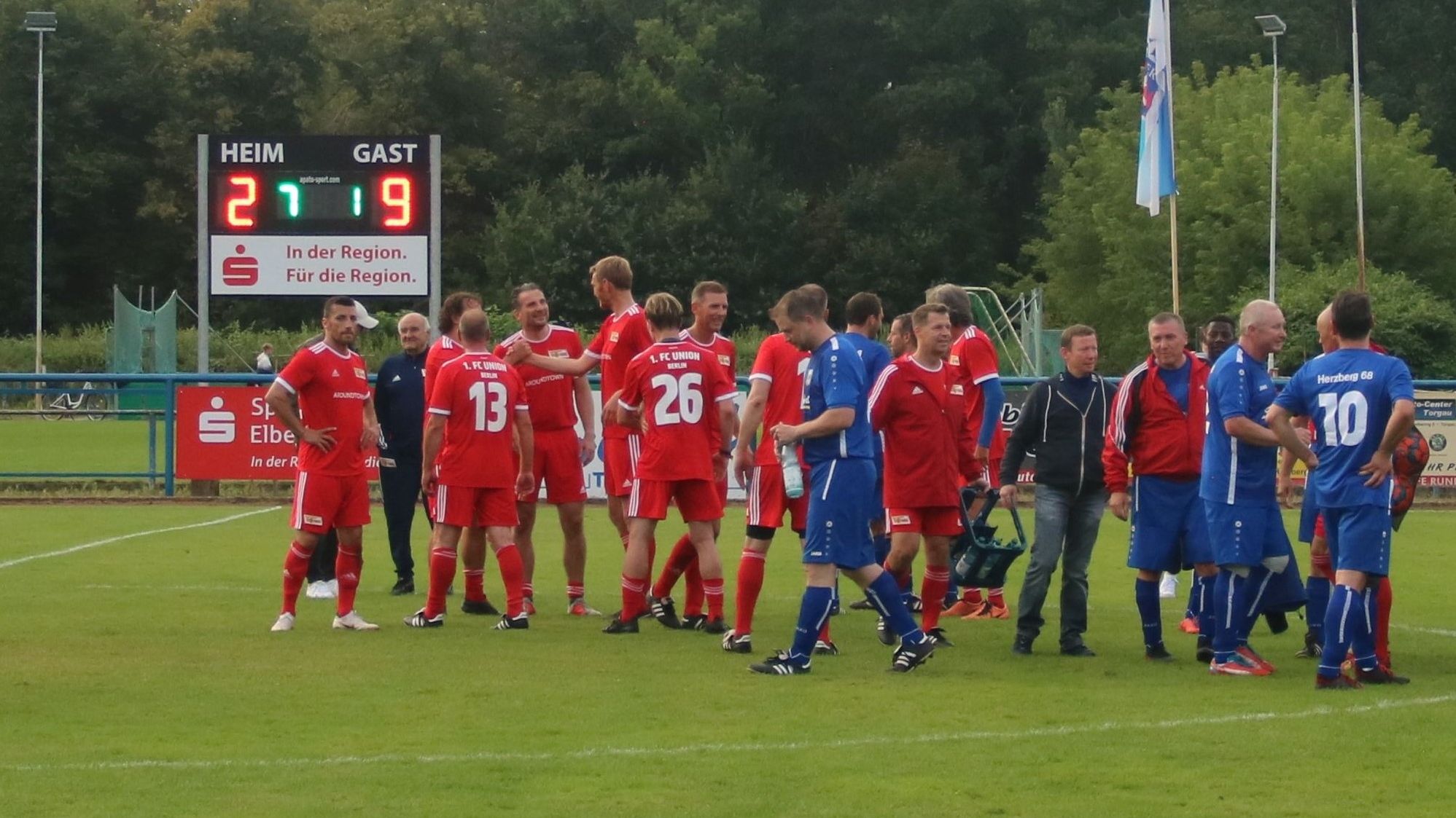 Spielszene eines Fußballspiels, Heimteam in roten Trikots und Gastteam in blauen Trikots auf dem Platz, Anzeigetafel zeigt 2:9 an.