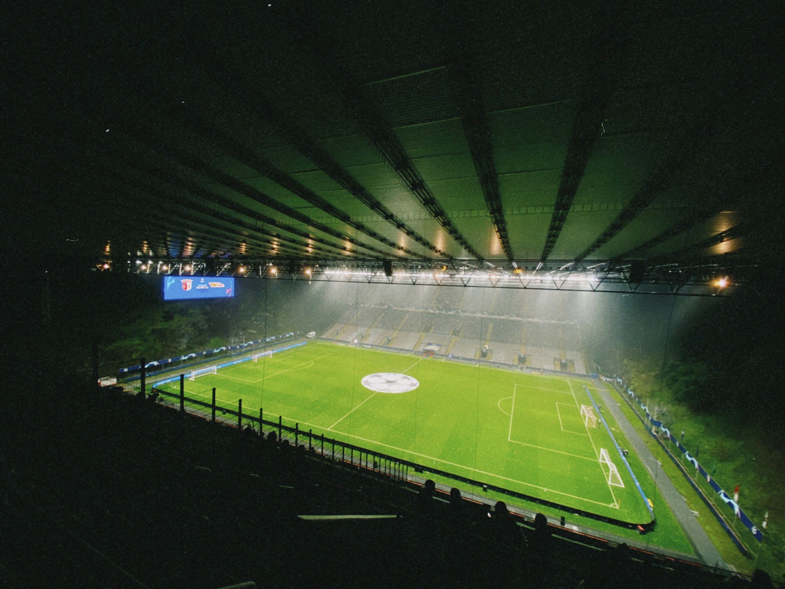 Campo de fútbol Nasser en un estadio, iluminado por luces, con público de pie en las gradas.