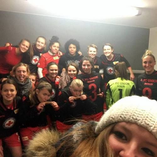 Gruppenselfie einer weiblichen Fußballmannschaft in Sportkleidung mit Roten Kreuz-Logos, lächelnd und posierend in einem Flur.