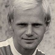 Schwarz-weiß Porträt eines Mannes mit blonden Haaren und einem neutralen Gesichtsausdruck, leicht lächelnd.