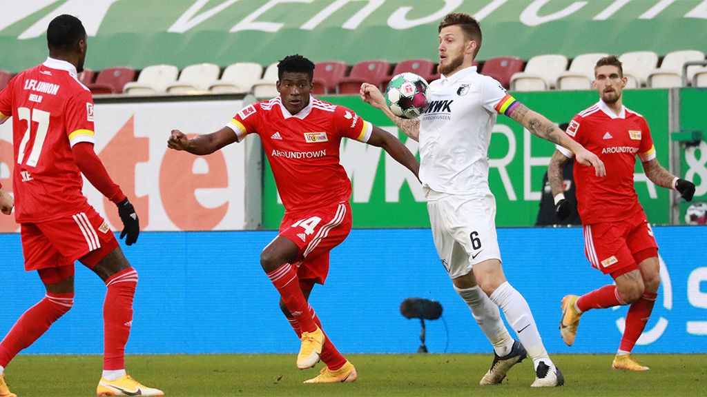 Zwei Fußballmannschaften in Aktion, Spieler im roten und weißen Trikot, ballführender Spieler wird verteidigt.