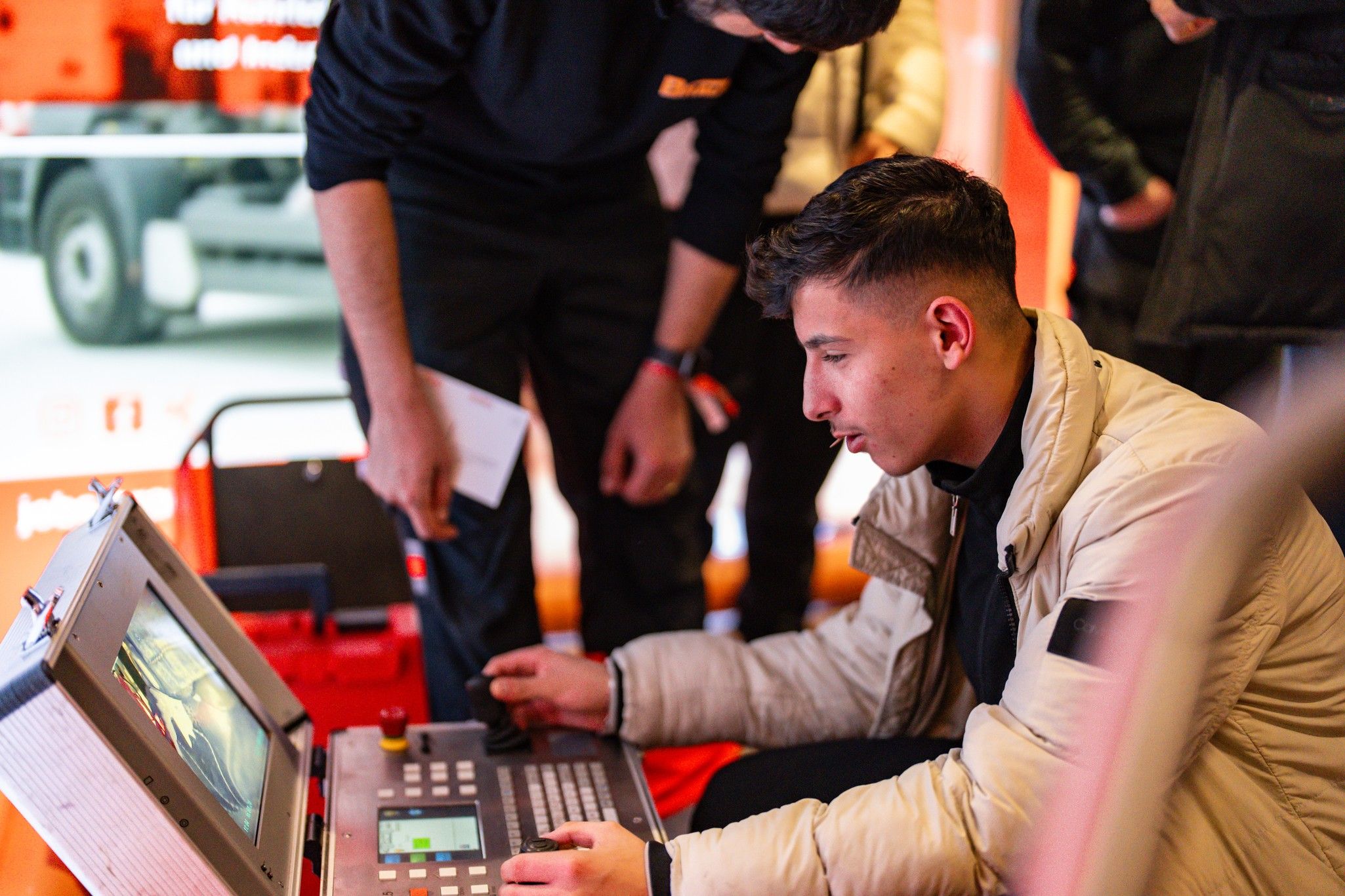 Ein junger Mann bedient einen Kontrollmonitor, während ein anderer Mann daneben steht und zuschaut.
