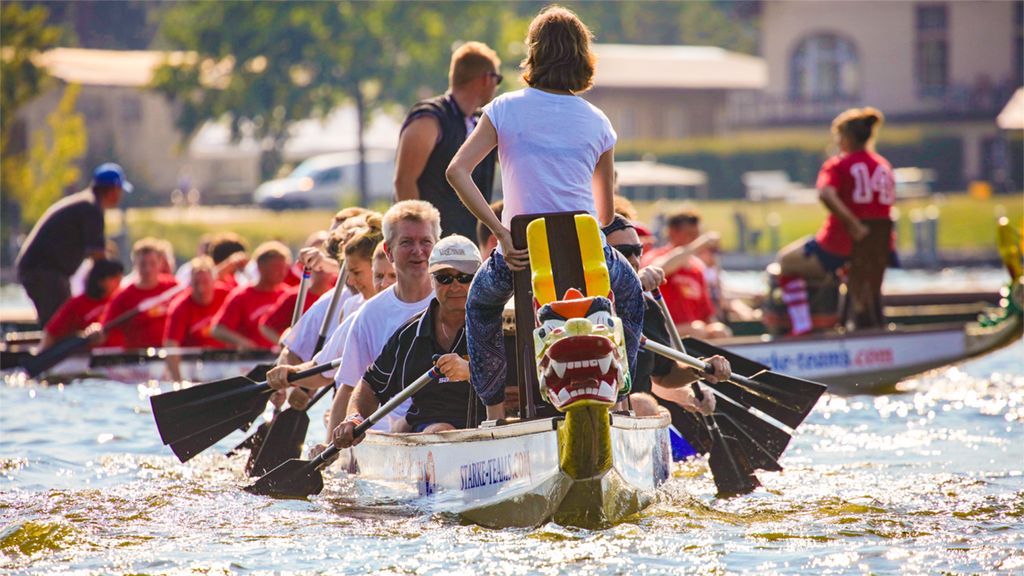 Group of people in dragon boats during a competition on a body of water, with a dragon head at the front of the boat.