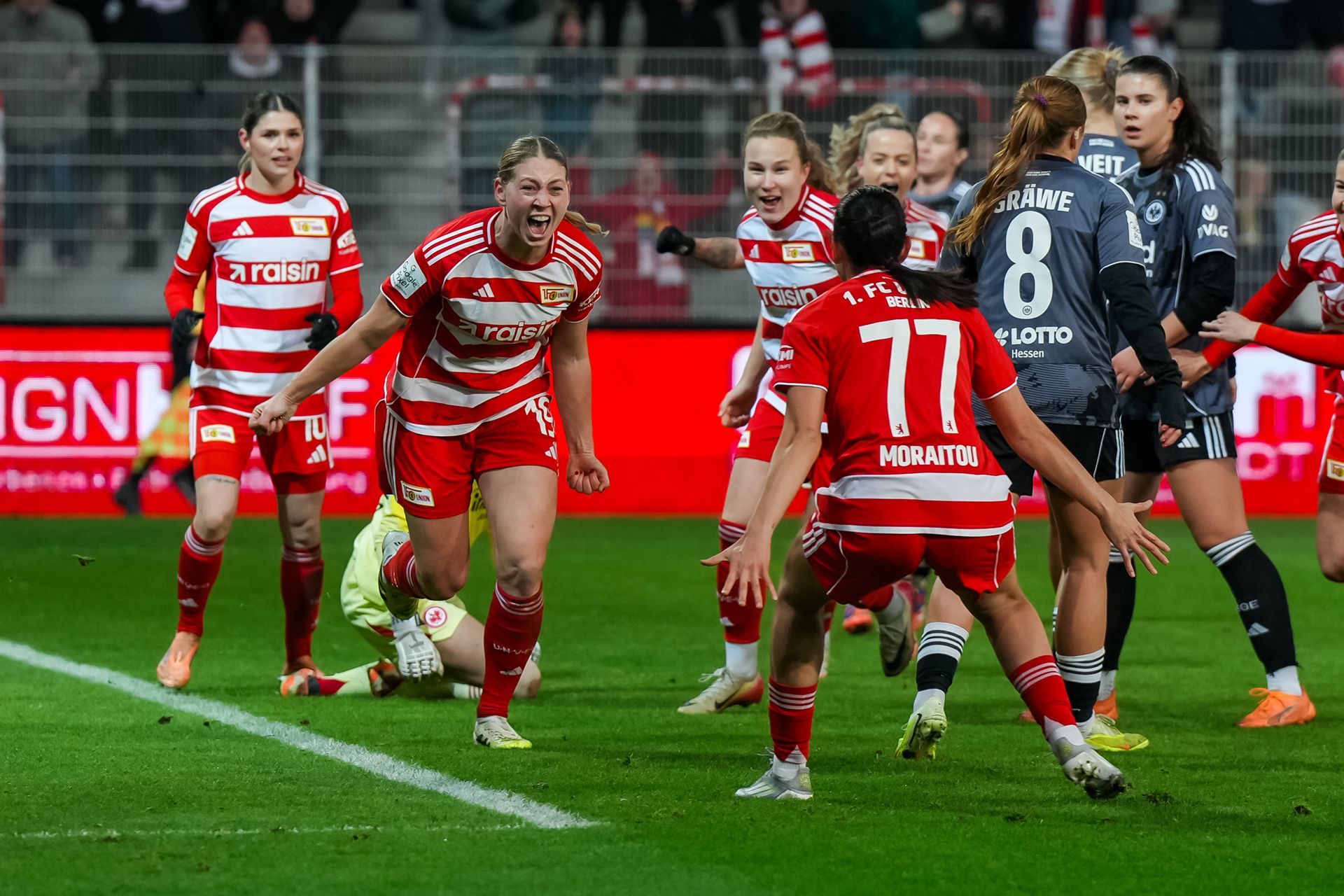 Spielerinnen des FC Union Berlin feiern einen Torerfolg während eines Fußballspiels, mit freudigen Emotionen und jubelnden Gesten.