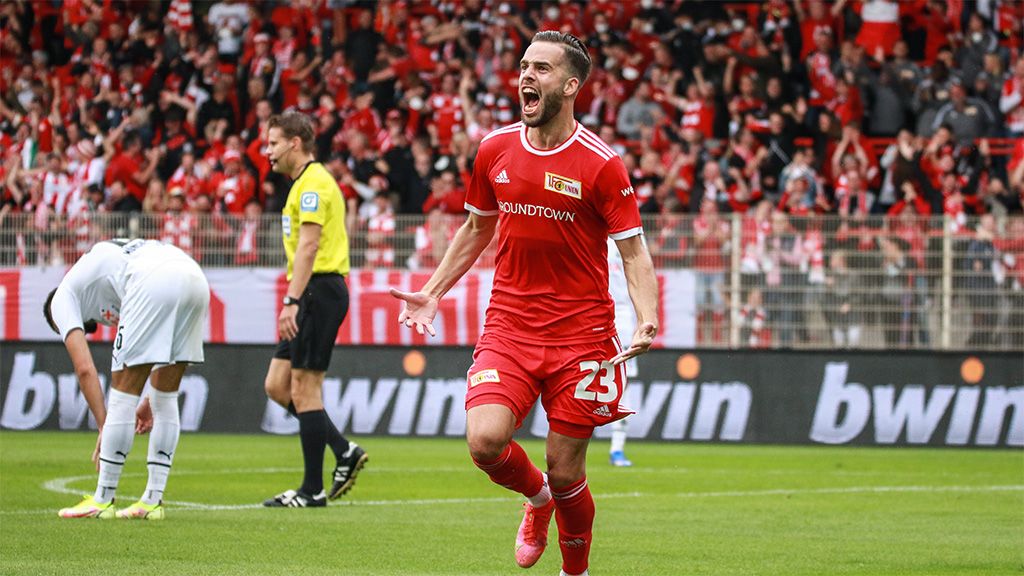 Ein Spieler von Union Berlin freut sich laut nach einem Tor. Die Fans feiern im Hintergrund.