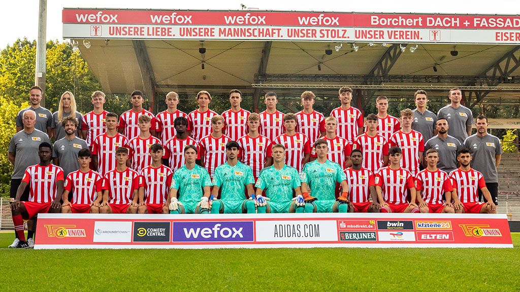 Mannschaftsporträt einer Fußballmannschaft in gestreiften Trikots, auf einer Tribüne in einem Stadion positioniert.