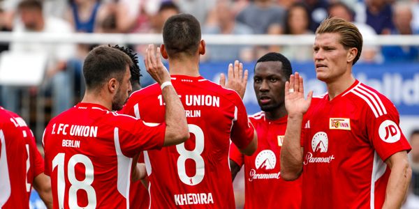 Players of 1. FC Union Berlin in red jerseys talking to each other before a game.
