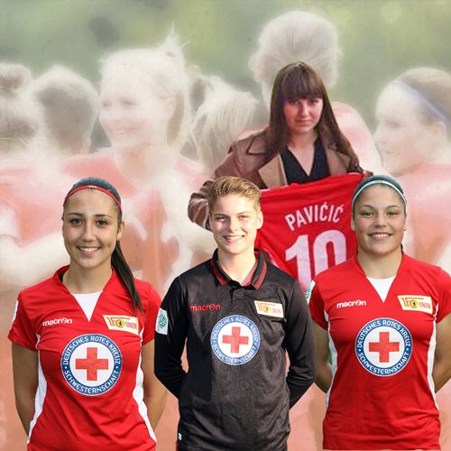 Drei Fußballspielerinnen in roten Trikots des Deutschen Roten Kreuzes stehen vor einer unscharfen Gruppenaufnahme.