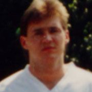 Verschwommenes Portrait eines Mannes in einem weißen Shirt, vor unscharfer, grüner Hintergrund.