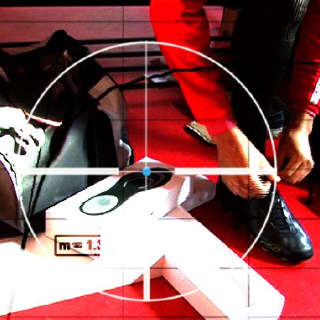 Person in rotem Oberteil schnürt schwarze Schuhe, während eine Sporttasche im Hintergrund steht. Zielscheibe über dem Bild.