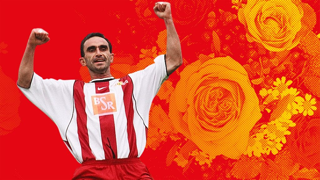 Ein jubilierender Fußballspieler in einem rot-weißen Trikot, vor einem roten Hintergrund mit Blumenmustern.