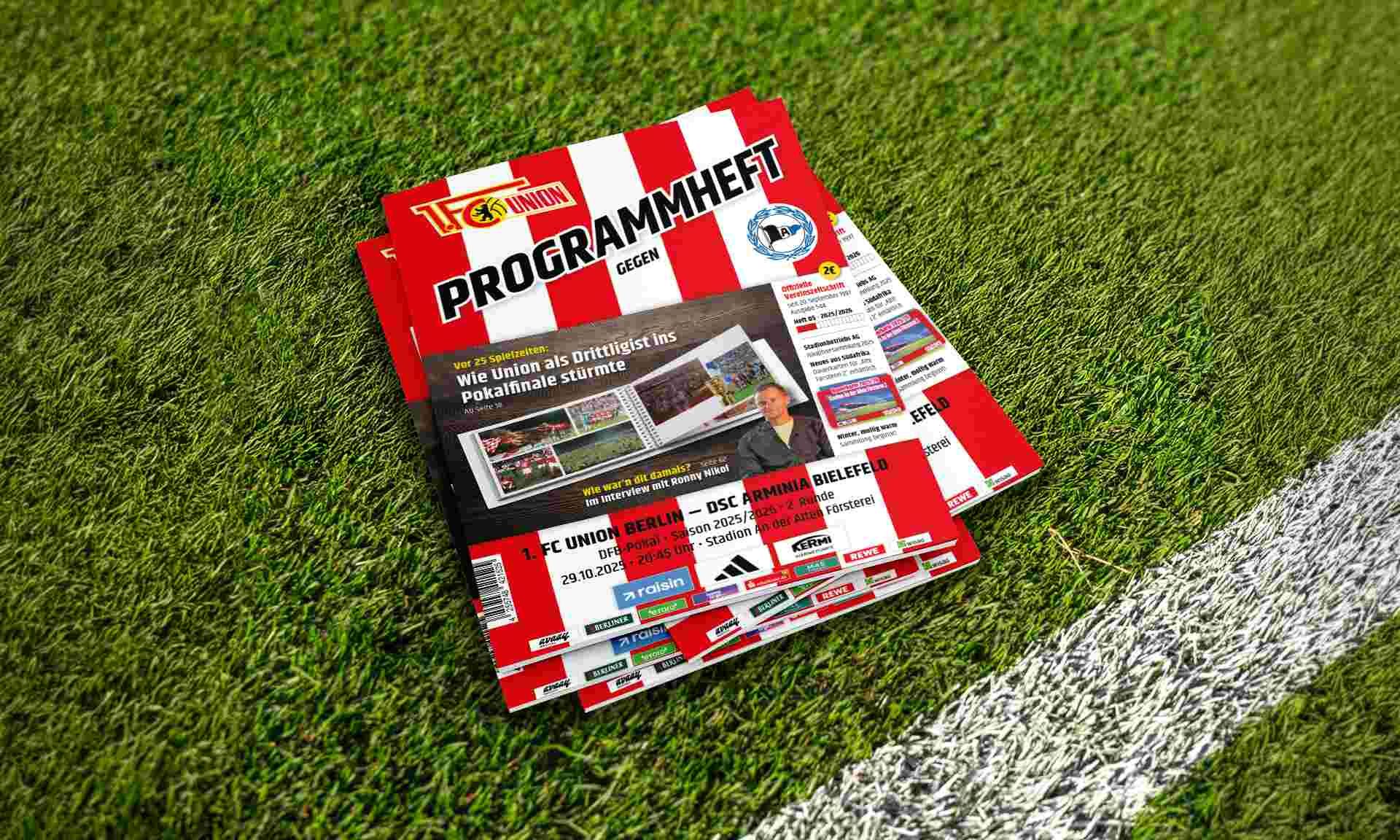 Programmheft der Fußballmannschaft 1. FC Union Berlin auf grünem Rasen mit weißen Linien.