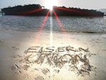 Schriftzug "EISERN UNION" im Sand, Sonnenstrahlen reflektieren auf Wasser, im Hintergrund ein Schiff.