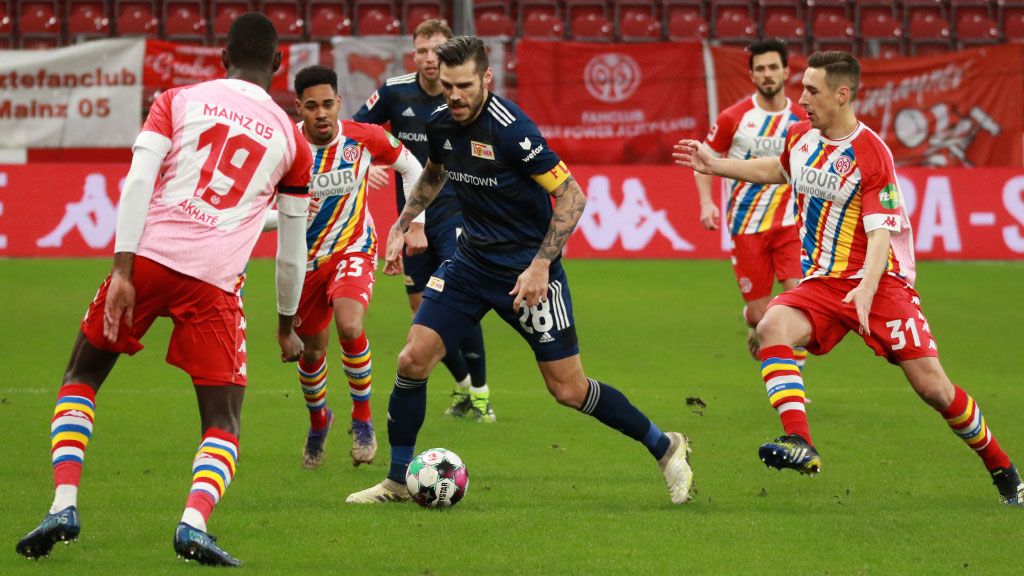 A football match between Union Berlin and Mainz 05. Players in colorful jerseys fight for the ball on the field.