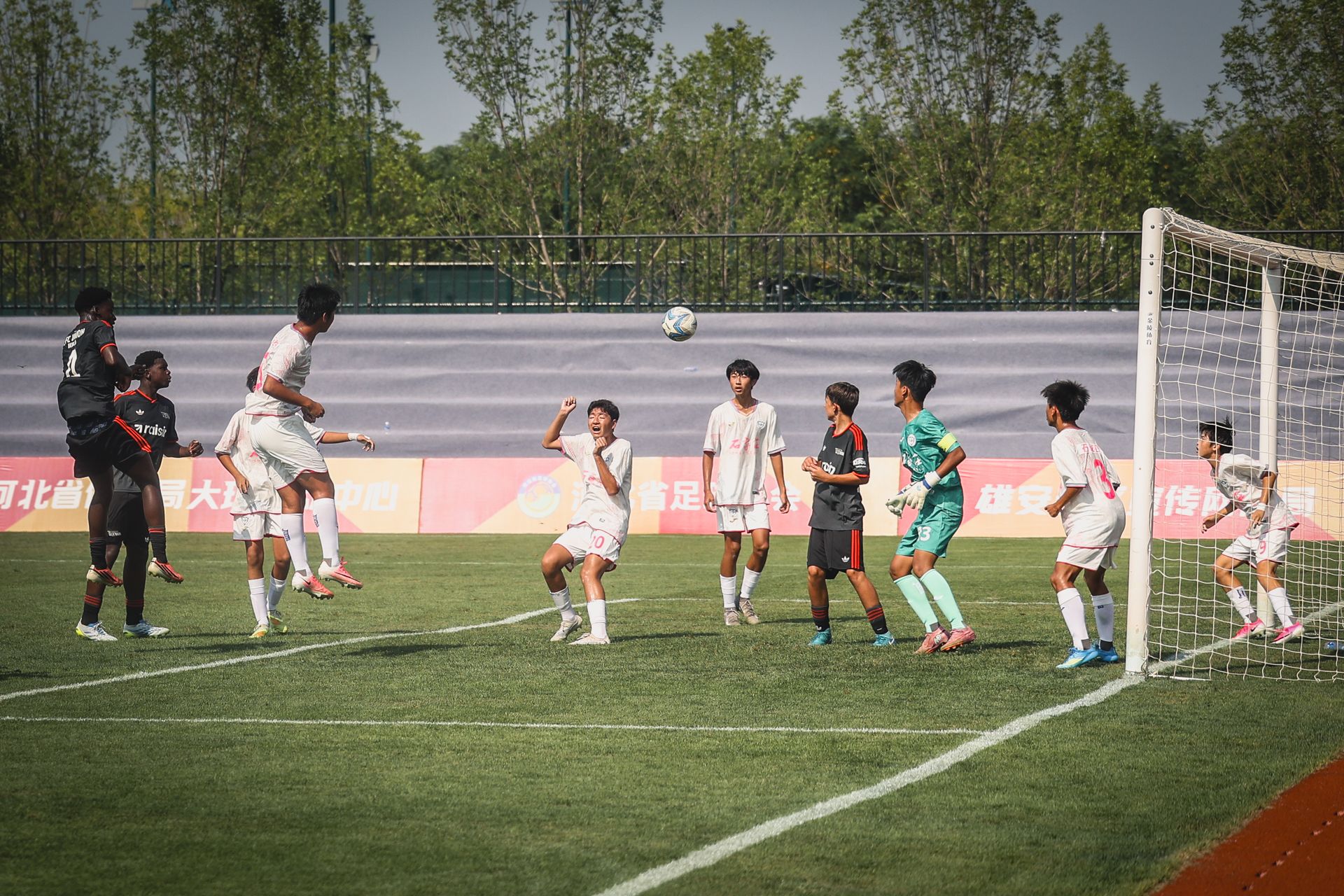 Eine Fußballszene, in der ein Spieler zum Kopfball ansetzt, während andere Spieler in der Nähe stehen und das Spiel beobachten.