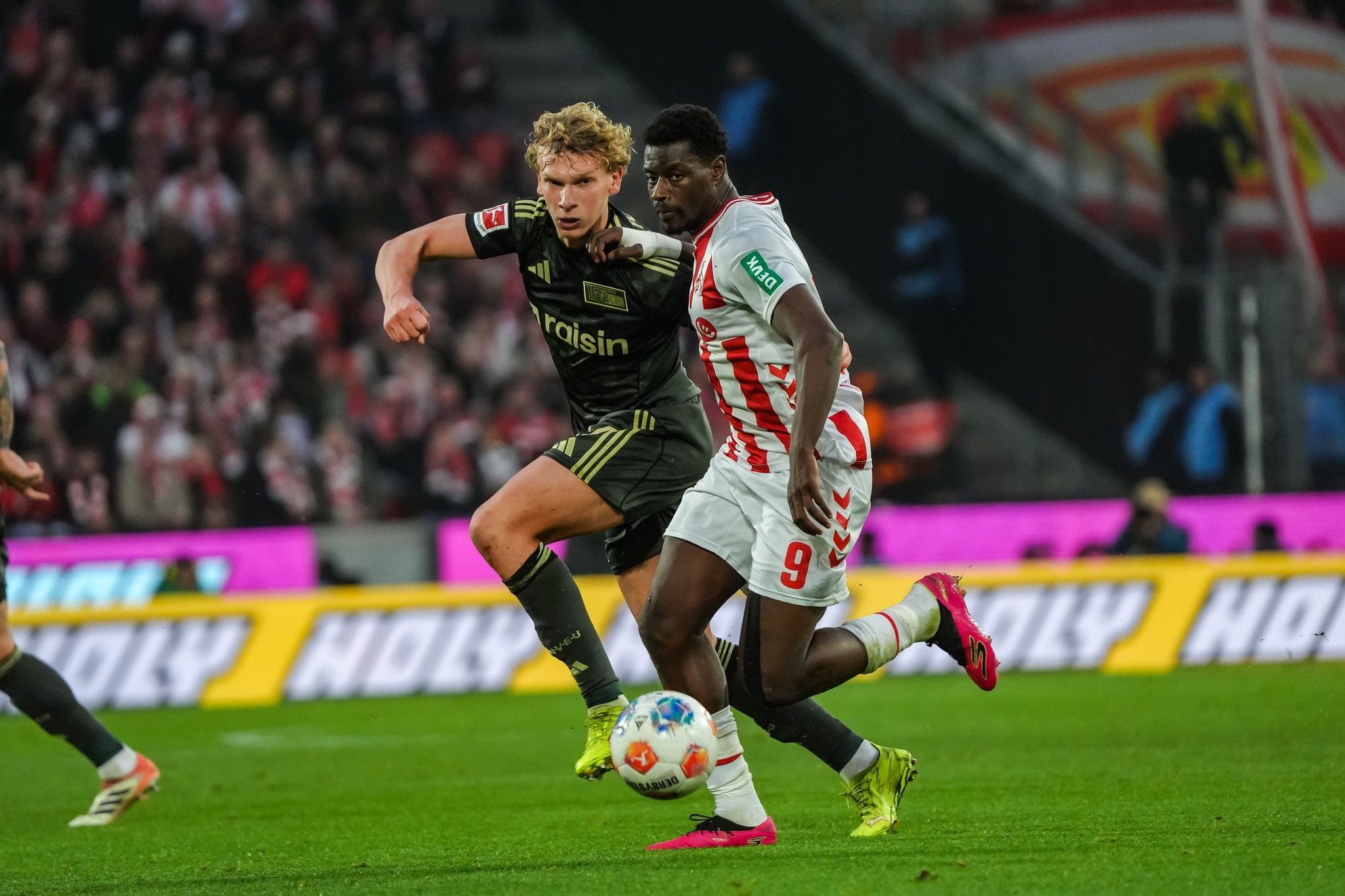 Zwei Fußballspieler im Wettkampf um den Ball während eines Spiels in einem Stadion.