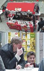 Markthalle mit einem Verkaufsstand, flankiert von zwei männlichen Personen, die an einem Tisch sitzen und etwas notieren.