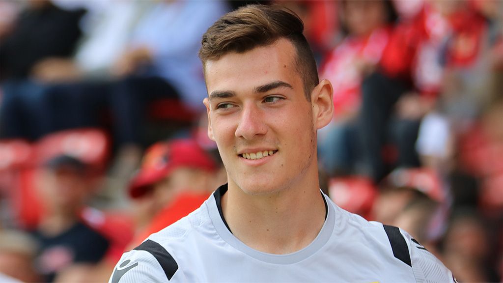 Young athlete in a jersey with a smiling face, blurred spectators in the background.