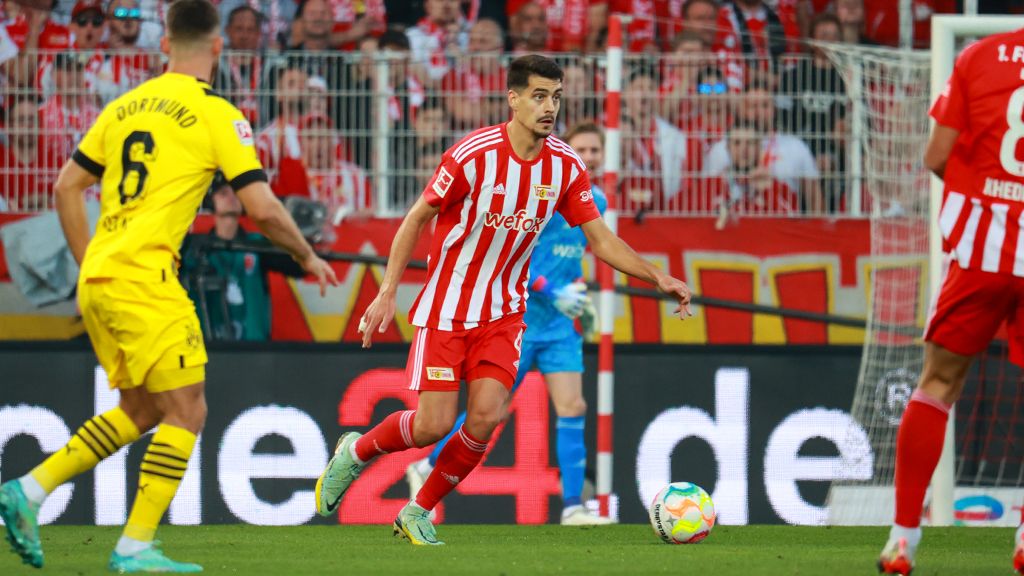 Spielszene im Fußballspiel zwischen Union Berlin und Borussia Dortmund, Spieler in gestreifter Uniform mit Ball am Fuß.