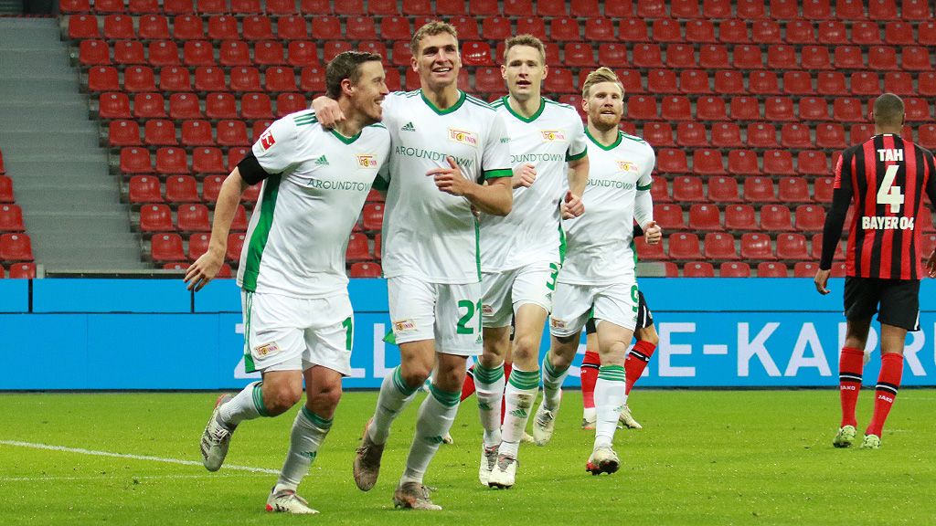 Fußballspieler der Mannschaft 1. FC Union Berlin jubeln nach einem Tor in einem Stadion mit leeren Sitzplätzen.