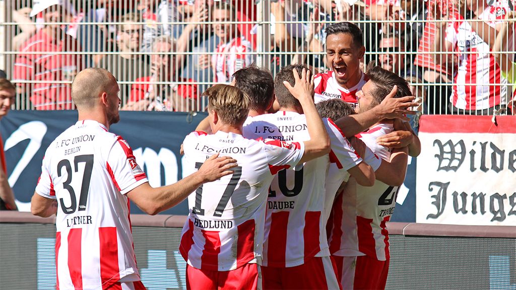 Spieler von Union Berlin feiern gemeinsam ein Tor, umgeben von jubelnden Fans im Stadion.