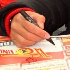 Eine Hand mit einem schwarzen Stift, die auf ein Papier zeichnet oder unterschreibt.