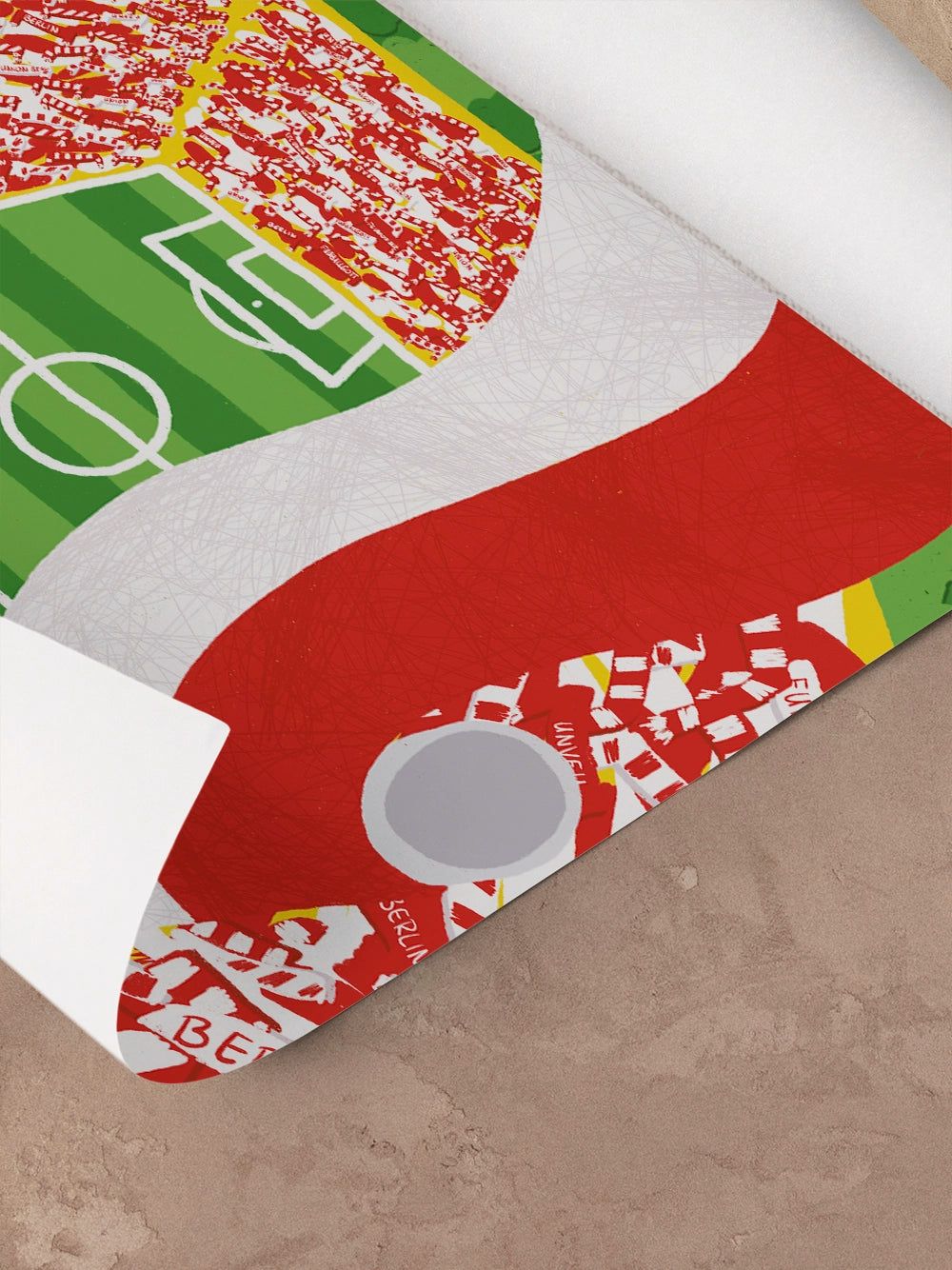 Eine gerollte Plakat- oder Wanddekoration zeigt ein Fußballfeld mit roten und weißen Mustern und Farben.