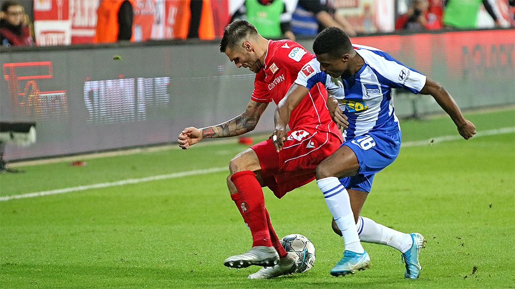 Zwei Fußballspieler kämpfen um den Ball während eines Spiels auf dem Spielfeld.