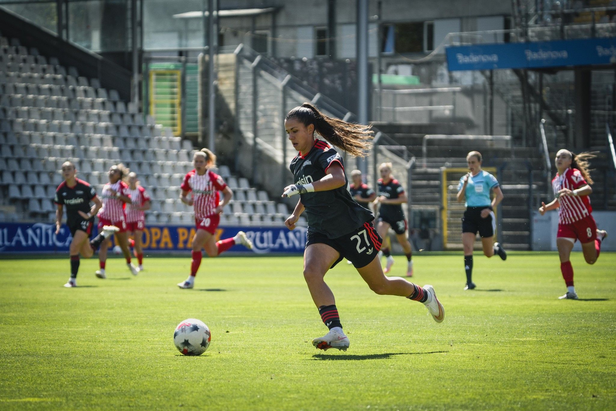 Torhüterin in Aktion, die einen Ball während eines Fußballspiels mit mehreren Spielerinnen im Hintergrund abfängt.