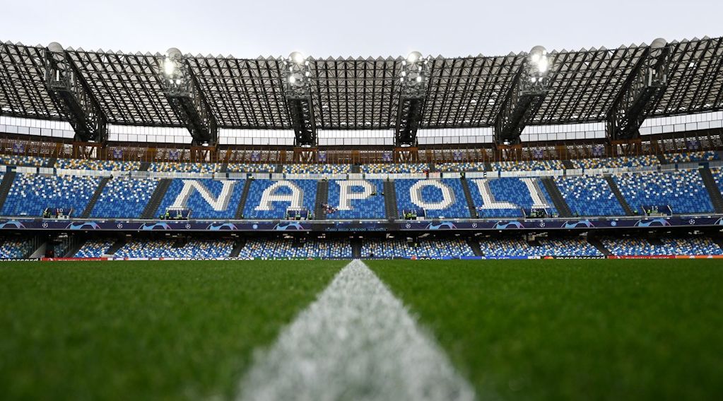 Blick auf das Stadion mit dem Schriftzug "NAPOLI" aus blauen und weißen Sitzplätzen, Rasenfläche und Linien im Vordergrund.