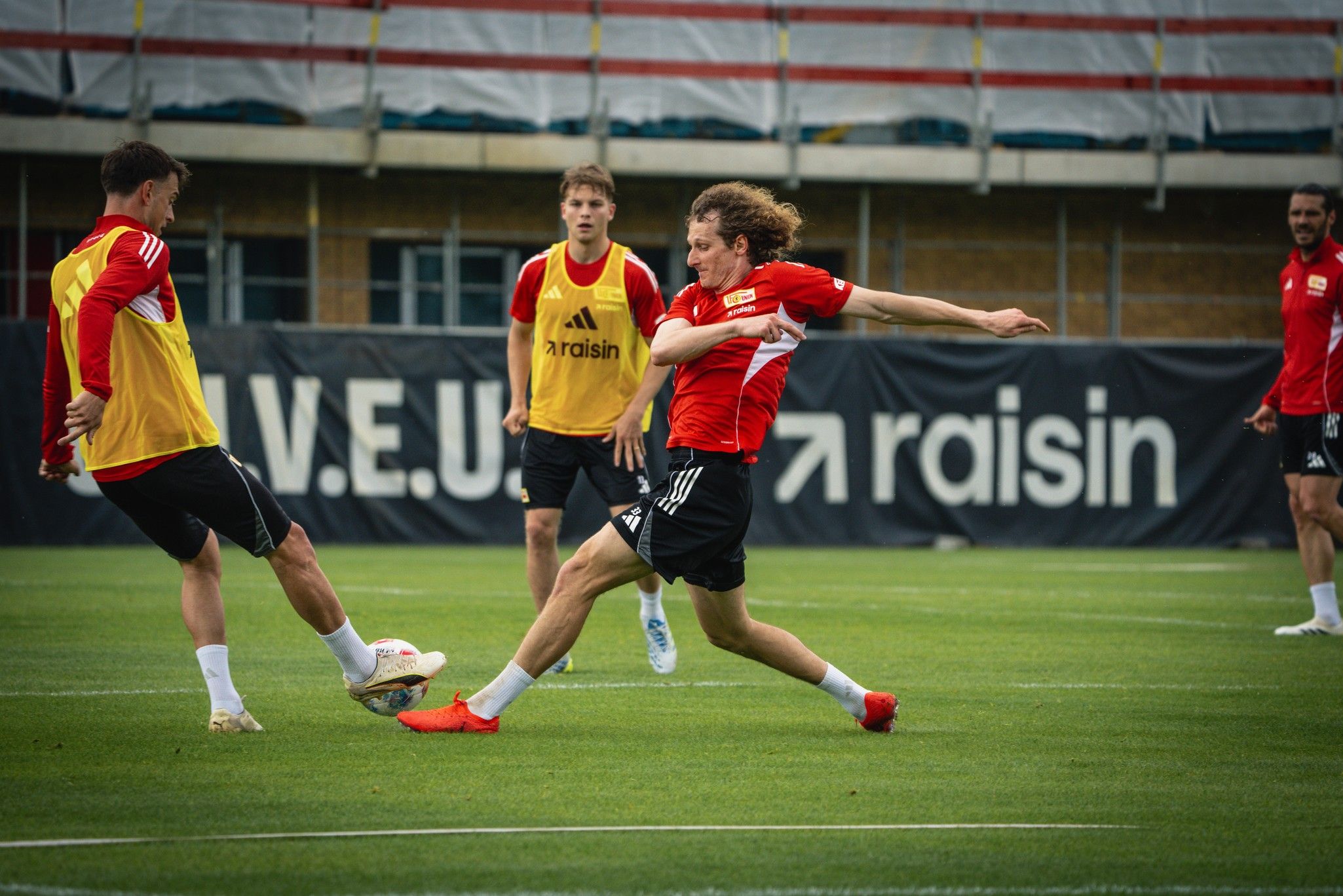 Spieler trainieren auf einem Fußballplatz, während einer einen Schuss auf das Tor abgibt.