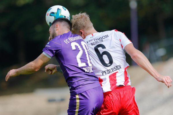 Zwei Fußballspieler kämpfen um den Ball, während sie in einem intensiven Duell aneinandergestoßen sind.