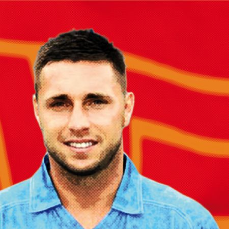 Ein Mann mit kurzem, dunklem Haar lächelt vor einem roten Hintergrund mit grafischen Elementen.