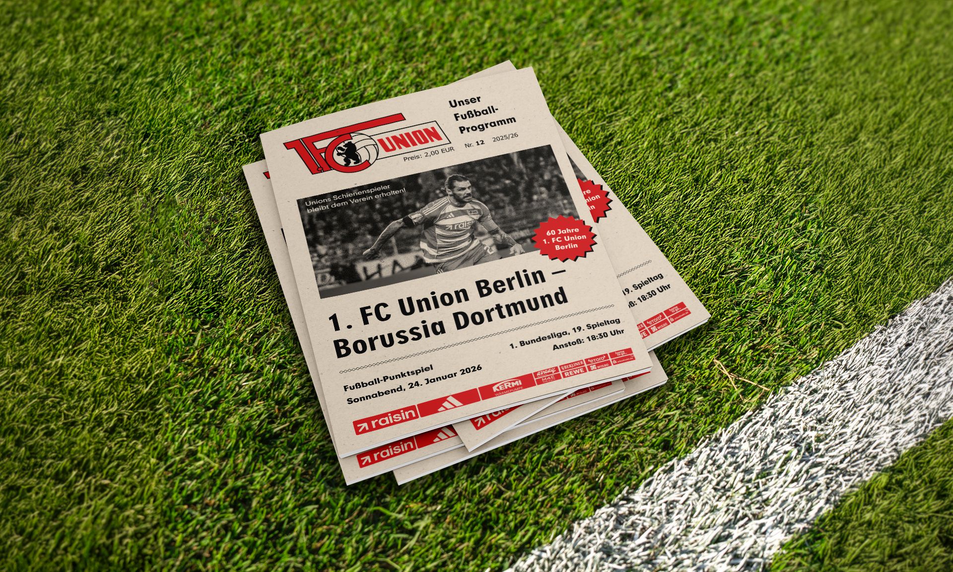 Programmhefte für das Fußballspiel 1. FC Union Berlin gegen Borussia Dortmund auf einem grünen Rasenfeld.