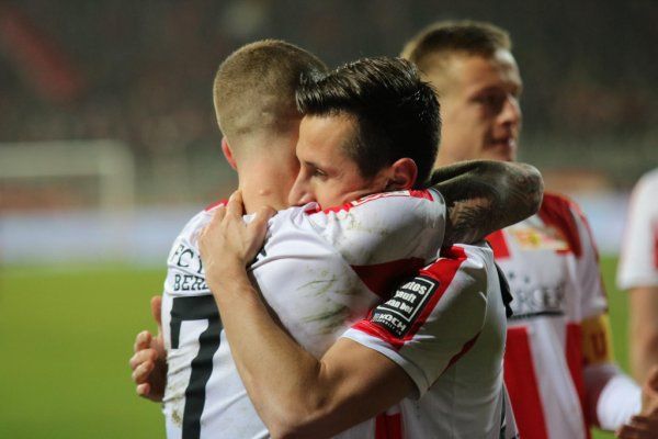 Two football players hug after a game, visibly happy and emotional.