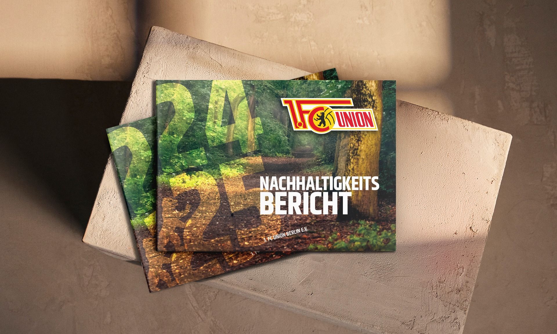 Zwei Heftchen mit dem Titel "Nachhaltigkeitsbericht" liegen auf einer neutralen, strukturierten Fläche.