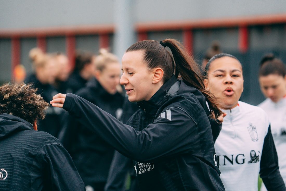 Eine Gruppe von Frauen in Sportkleidung beim Fußballtraining, einige lachen und interagieren.