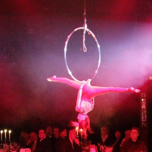 Eine Artistin führt akrobatische Übungen in einem Ring während einer Illumination in rotem Licht auf.