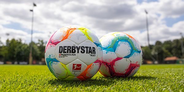 Two colorful soccer balls, each with the "Derbystar" and "Bundesliga" logo, are on fresh green grass.
