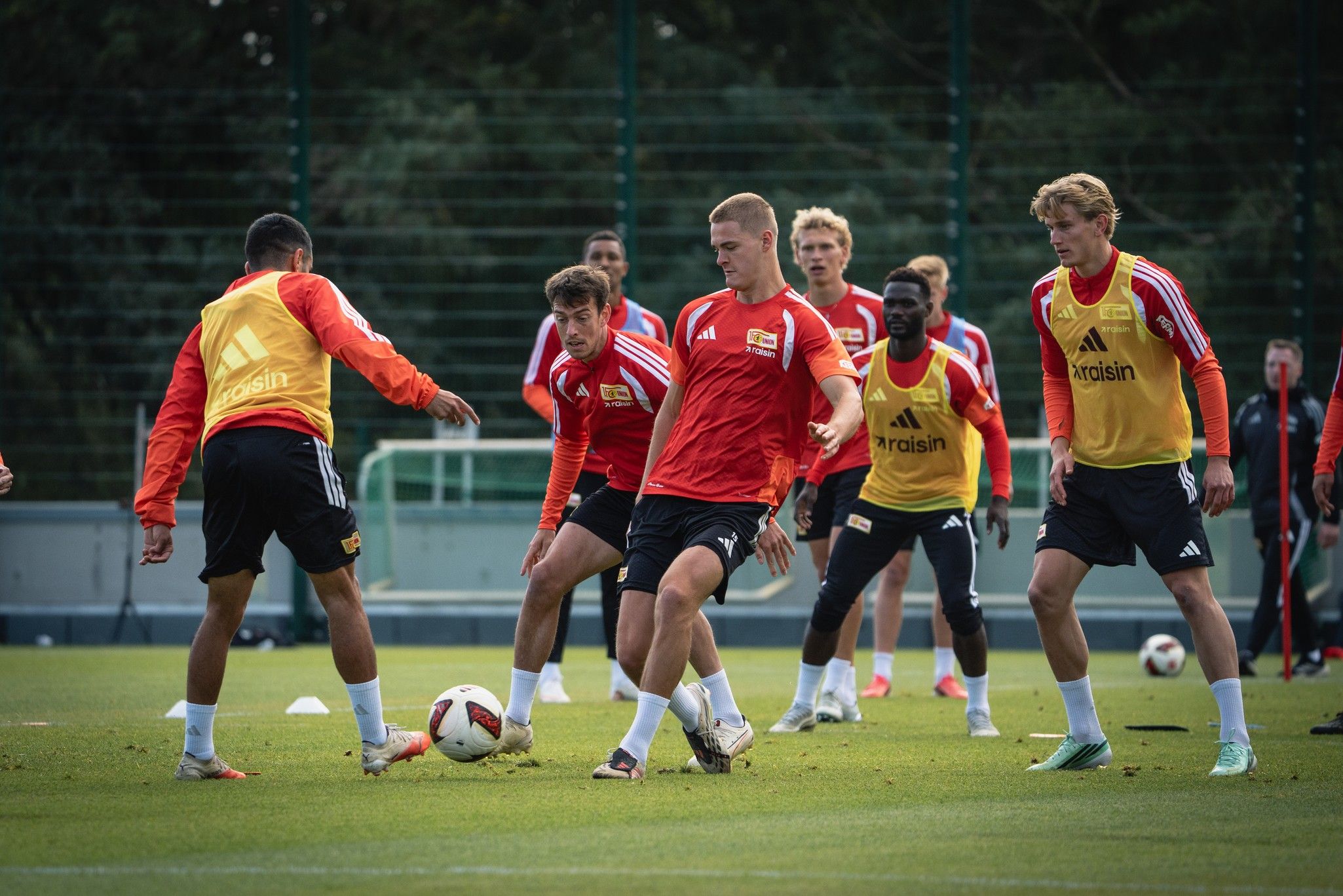 Spieler in Trainingskleidung üben auf einem Fußballfeld, während sie den Ball passen und sich auf das Training konzentrieren.