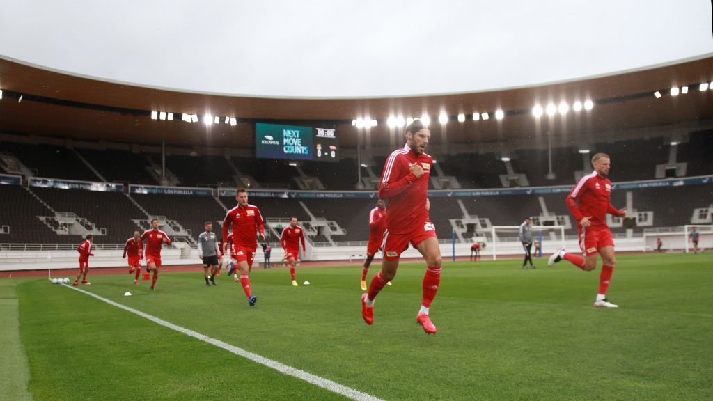 Fußballspieler in roten Trikots laufen auf dem Spielfeld eines Stadions während eines Trainings.