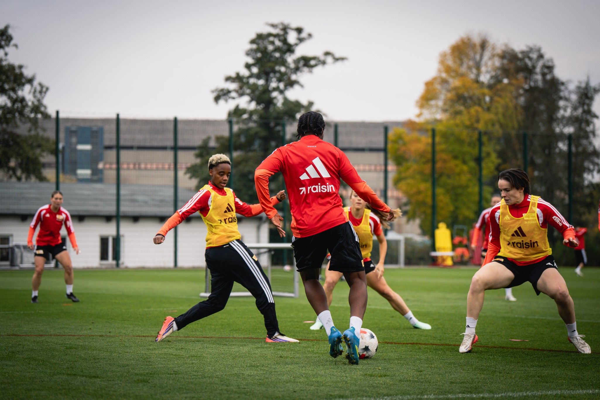 Eine Gruppe von Frauen in rot-weißen Sporttrikots trainiert auf einem Fußballplatz.