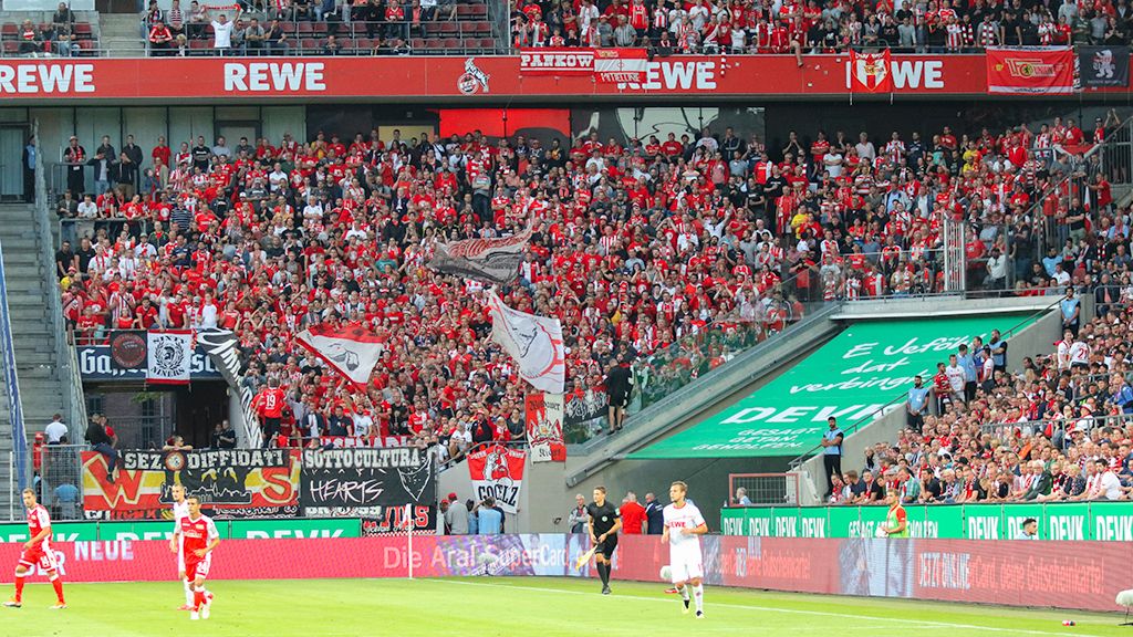 A fully packed stadium with happy fans holding flags and banners.