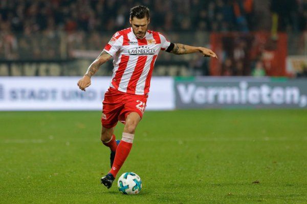 A soccer player in a red and white jersey kicks the ball on the field.