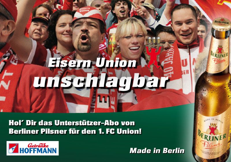 Fans mit Flaggen und Schals in den Farben von Eisern Union, jubelnd im Stadion, mit einem Bier neben dem Text „Eisern Union unschlagbar“.
