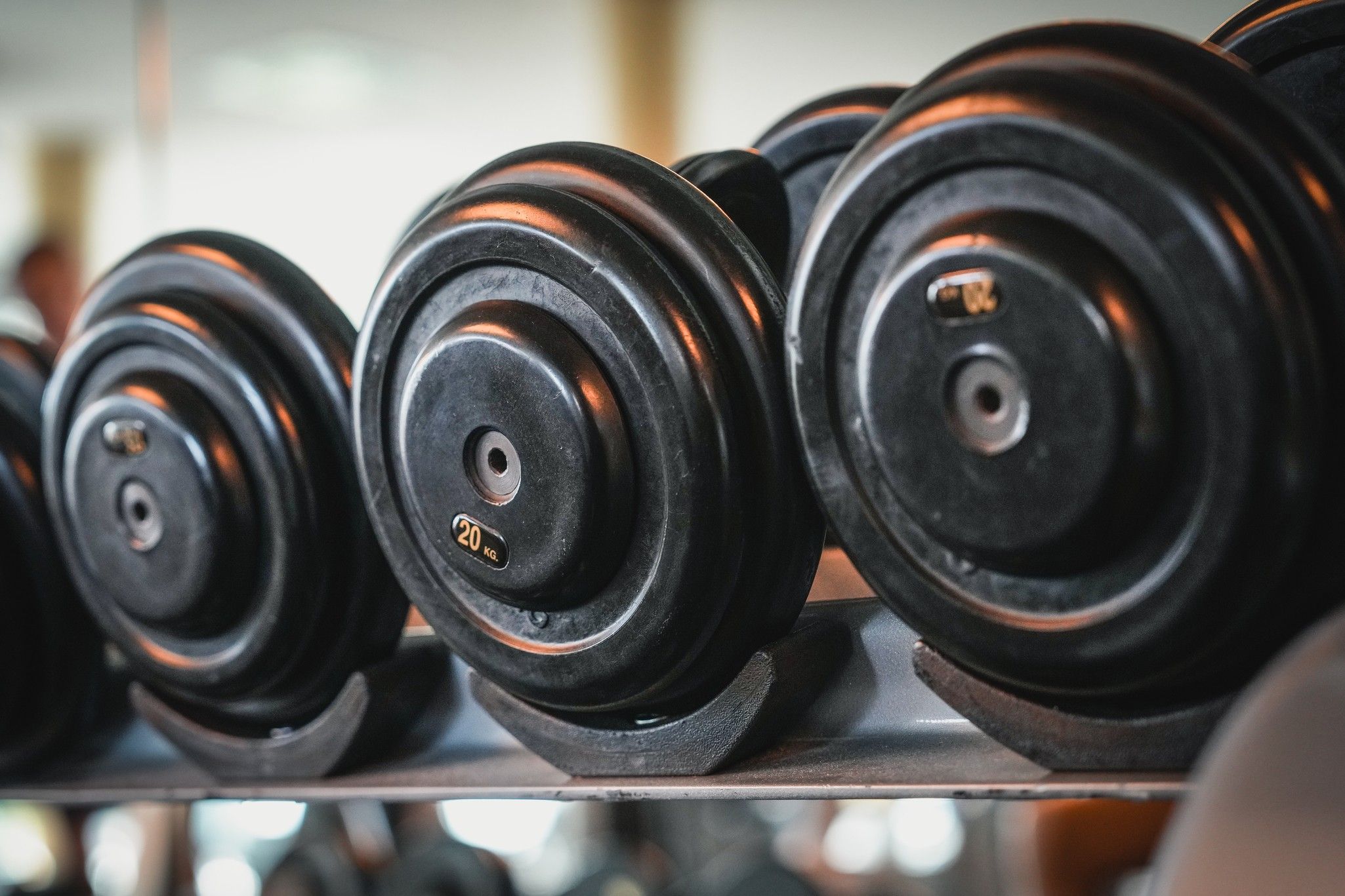 Eine Reihe von schwarzen Hanteln mit sichtbaren Gewichtsangaben, auf einem Gestell in einem Fitnessstudio.
