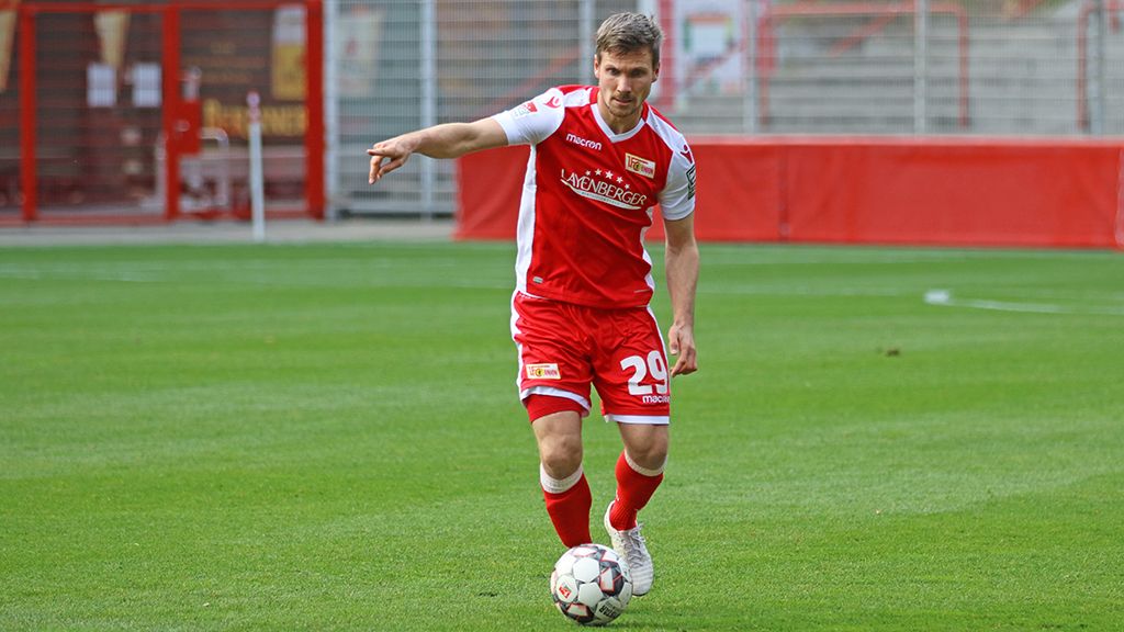 A soccer player in red and white club attire is dribbling the ball on a grassy field.