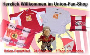 Willkommensbanner für den Union-Fan-Shop mit Fanartikeln, Shirts, Kissen und einem Stofftier.