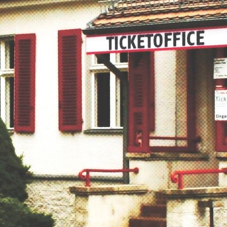 Blick auf ein Ticketbüro mit roten Fensterläden und einem kleinen Eingangsbereich.