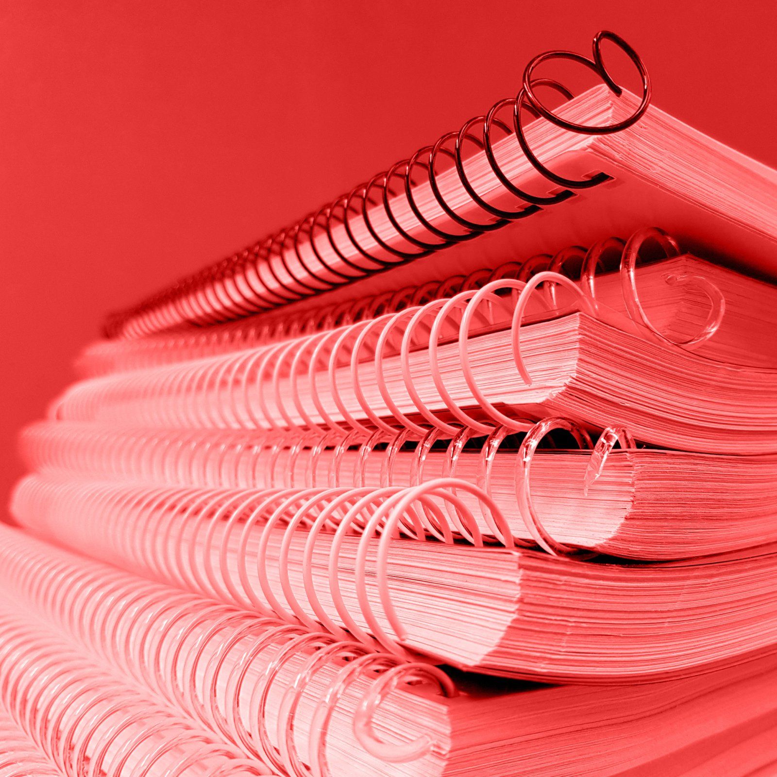 Ein Stapel von Spiralbindern auf rotem Hintergrund.